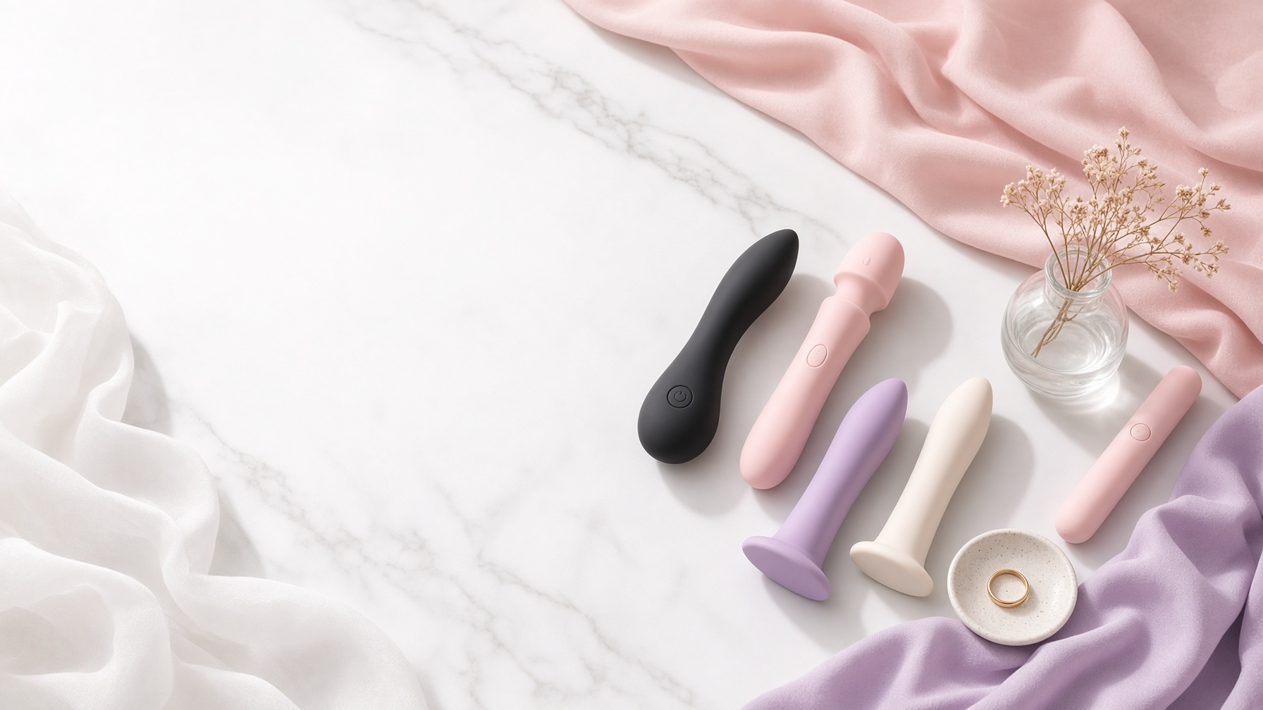 An assortment of silicone vibrators and dildos arranged on marble with draped fabric